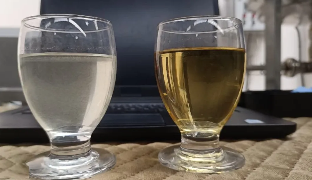 Two glasses of coconut water samples side by side on a bench, one clear and one golden, at the PrimeCoco facility