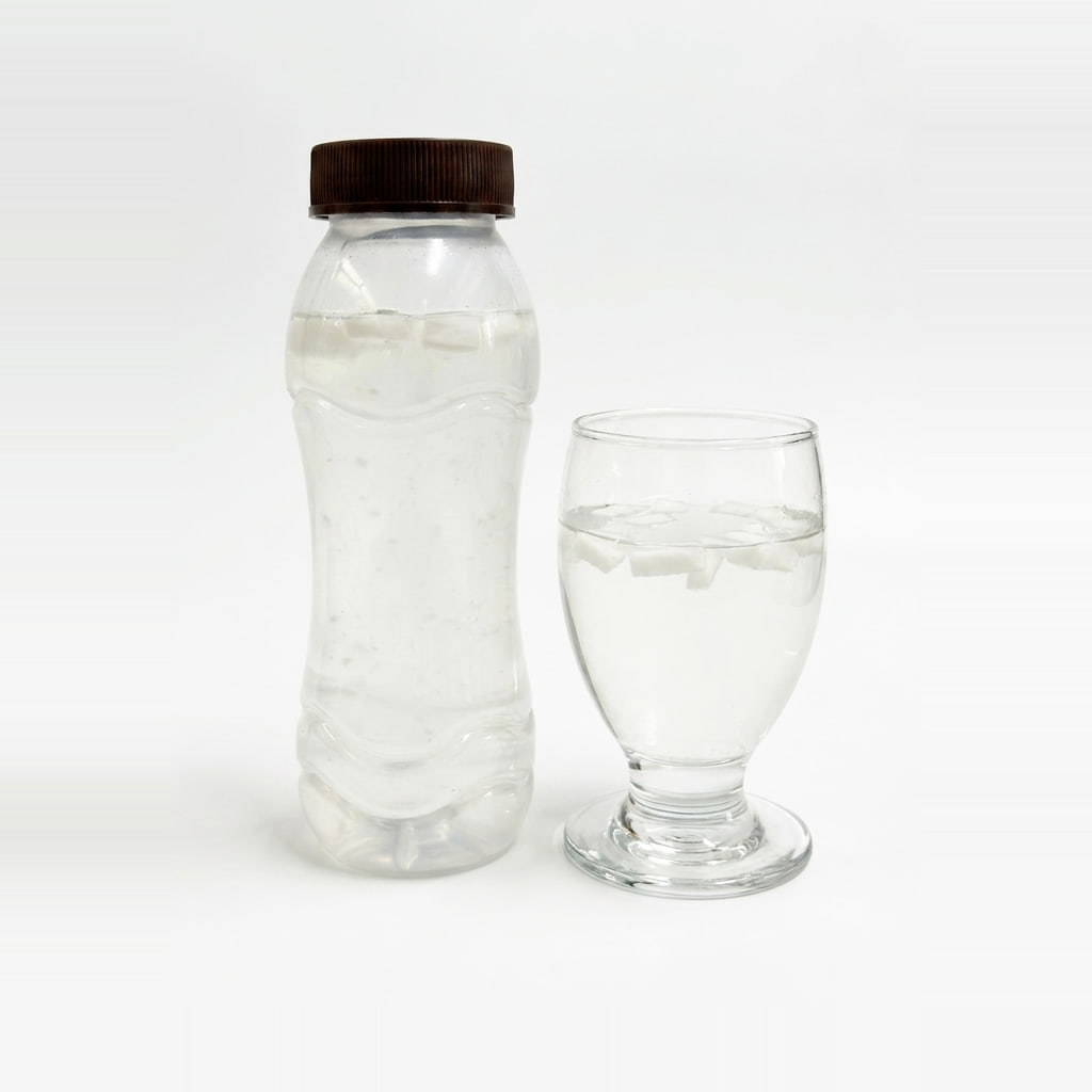 Bottled PrimeCoco coconut water with firm white coconut chunks floating at the top